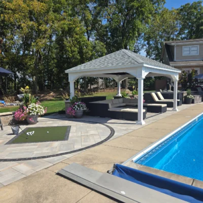 Vinyl pavilion with a gray shingle roof overlooking a swimming pool and patio area by Carrington Lawn & Landscape