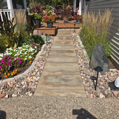 Close-up of a stone pathway through a garden, with colorful flowers, decorative rocks, and tall grasses by hardscape design contractors in Middleton, WI
