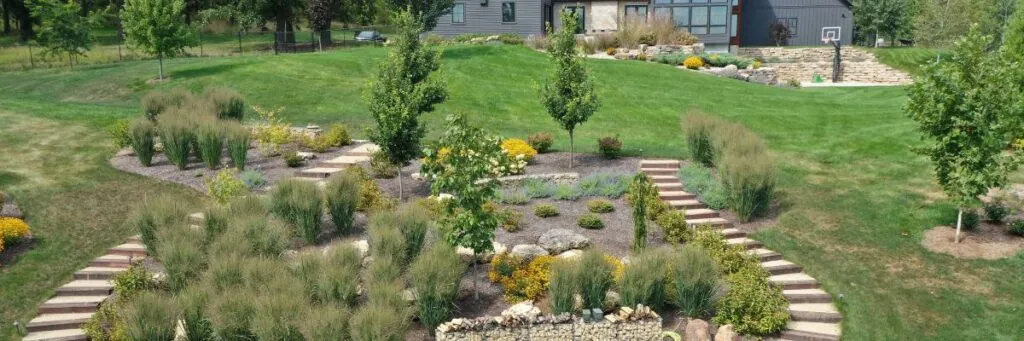 Tiered landscaping with stone steps, ornamental grasses, and flowering plants that had landscape design services by Carrington Lawn & Landscape in Middleton, WI