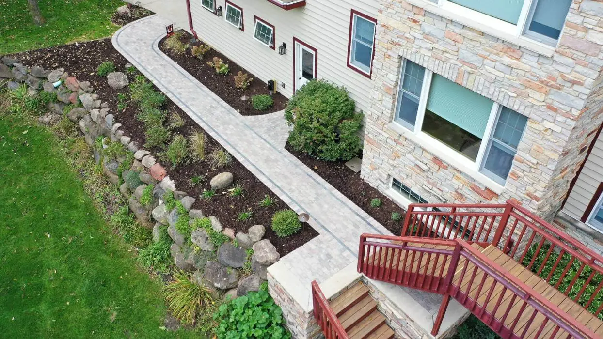 A flower bed with a variety of colorful flowers, ornamental grasses, and a neatly trimmed hedge in Middleton WI