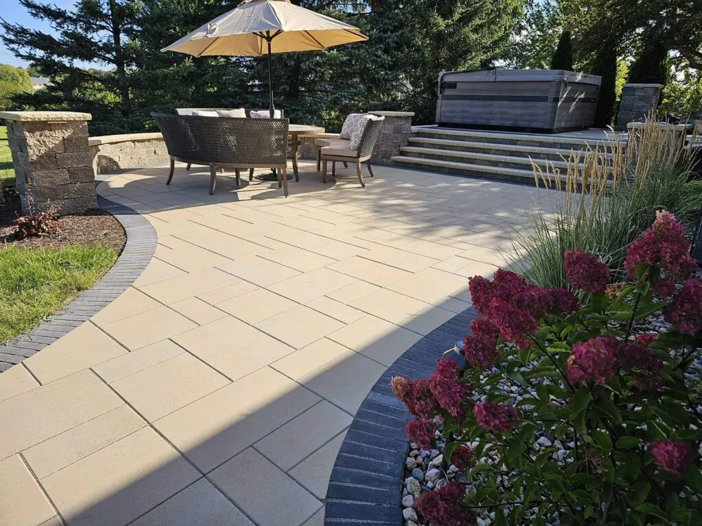 Patio with seating and hot tub, showcasing hardscape design with pavers and stone accents.