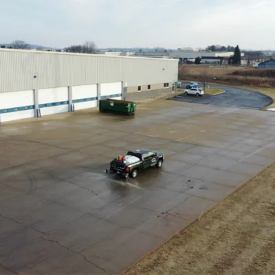 Carrington Lawn & Landscape snow and ice management truck on an empty commercial parking lot, clearing ice in Madison, WI