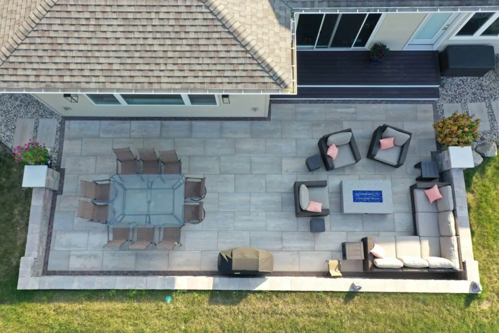Hardscape design patio with dining and lounge areas, fire pit, and grill next to a house in Madison, WI