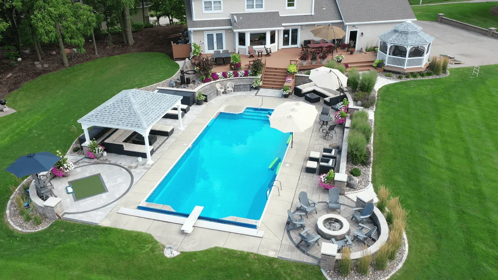 Luxurious backyard pool area with gazebo and fire pit, designed by Carrington Lawn & Landscape