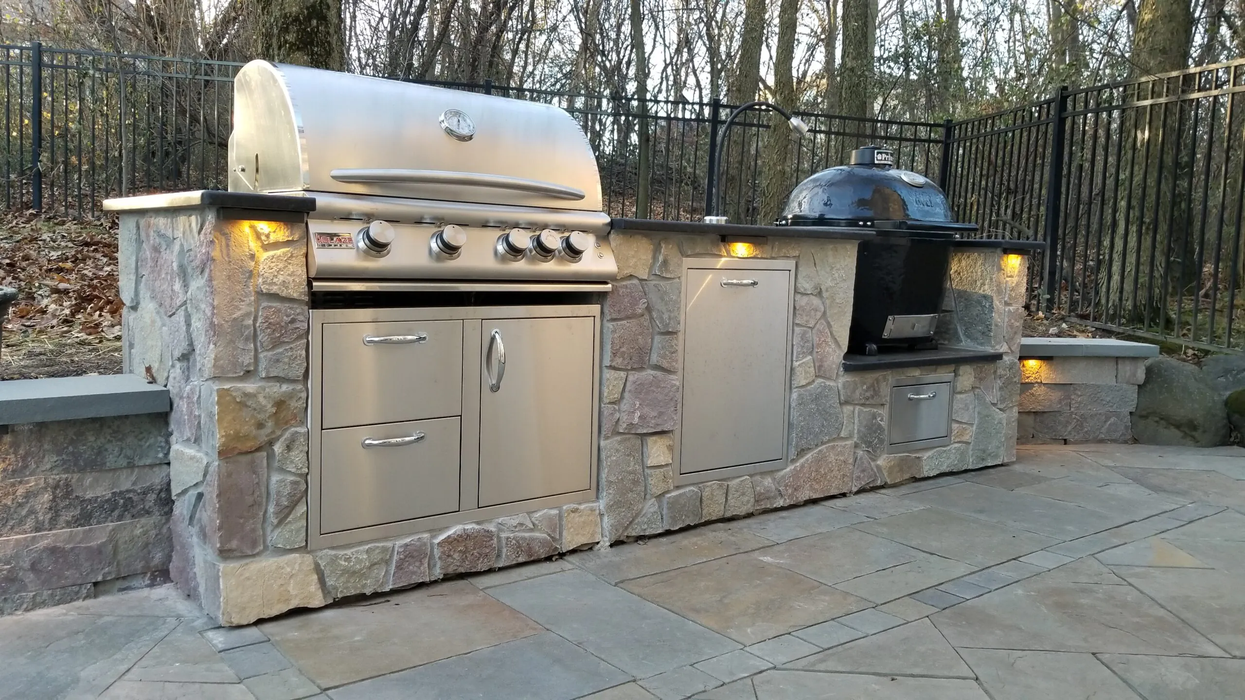 A built-in stone outdoor grill island with a gas grill and smoker, supporting outdoor kitchen middleton wi in Middleton by Carrington Lawn & Landscape.