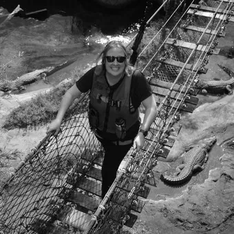 Amanda, A Carrington Lawn & Landscape team member, walking across a rope bridge over crocodiles