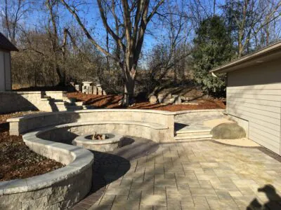 A curved stone fire pit seating area with patio pavers, showing fire pit design ideas 2026 and fire pit renovation ideas in Middleton by Carrington Lawn & Landscape.