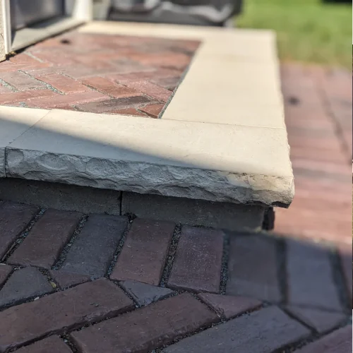 Stone-edged patio step with brick inlay showing expert hardscape design and Madison landscape design by Carrington Lawn & Landscape in Madison
