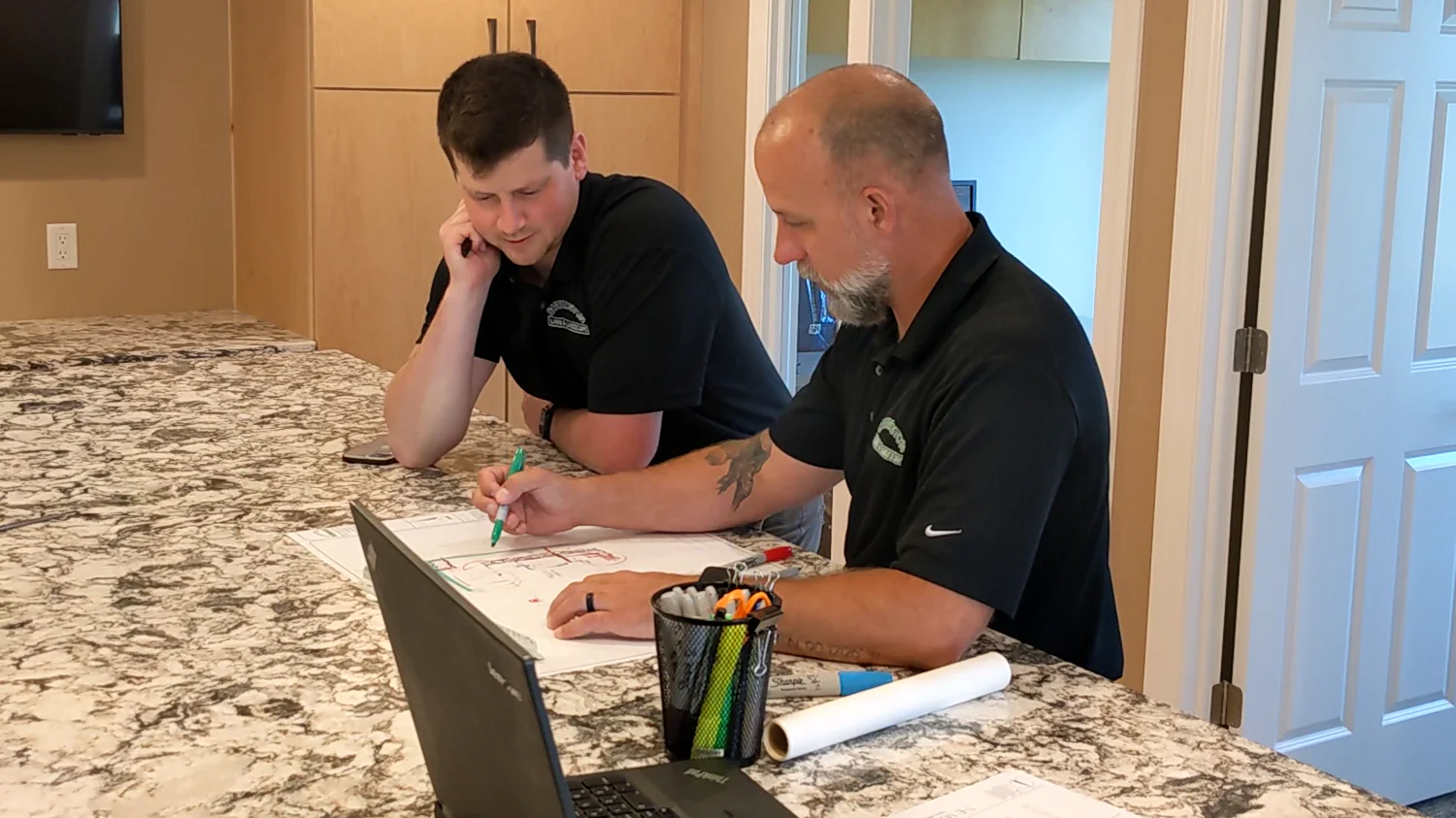 Two professional landscapers reviewing blueprint plans together at a counter during early landscape design process steps, providing expert landscape design process services in Middleton, Wisconsin by Carrington Lawn & Landscape.